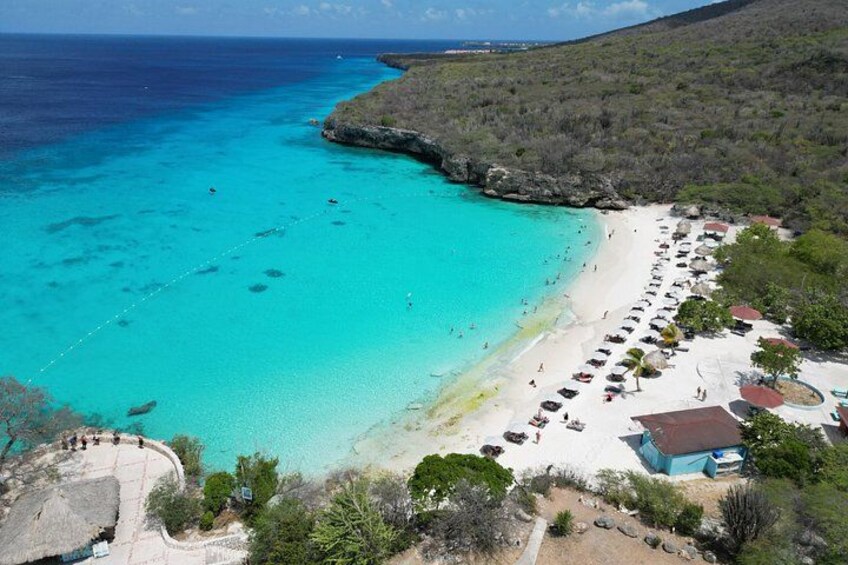 A turquoise beach with clear waters, a sandy shore, and a few people. 2