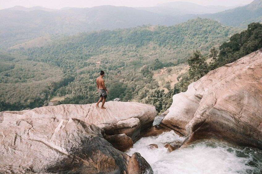 A man standing on a rock overlooking a river and a mountainous landscape. 2
