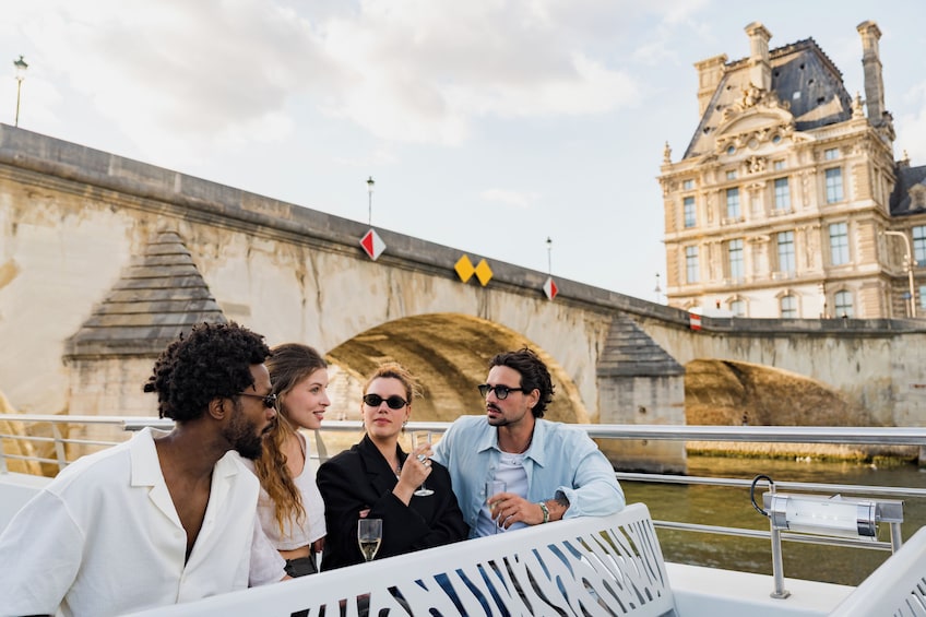 A group of people on a boat near a historic bridge with a large building in the background. 4