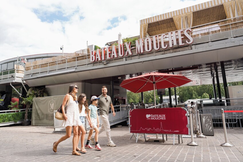 A family walking towards a building with a sign reading 'Bateaux-Mouches'. 5