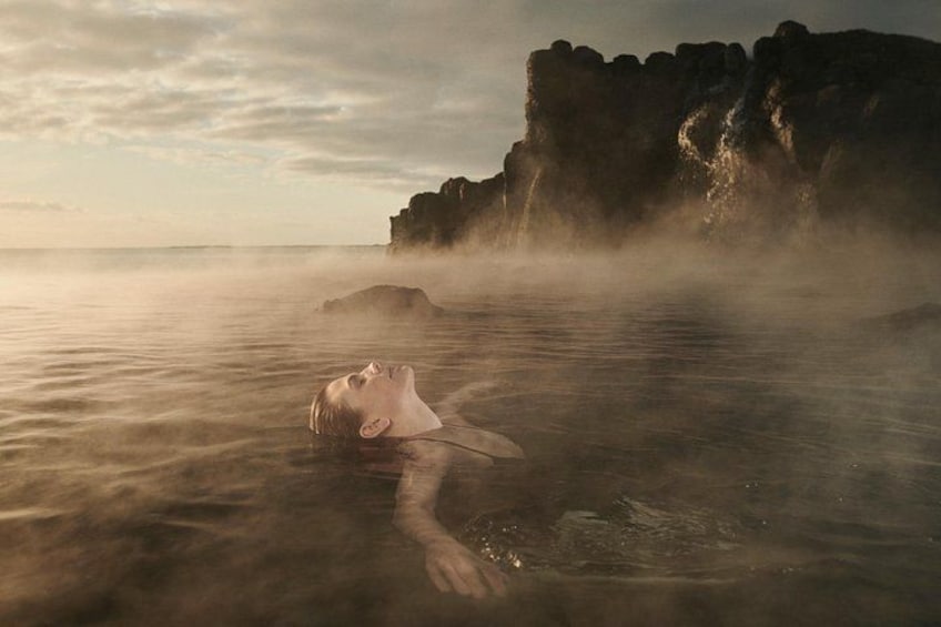 Una persona immersa nell'acqua nei pressi di scogliere rocciose. 2