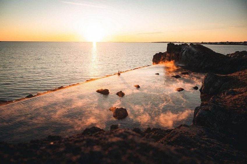 A sunset over a rocky coastline with calm water reflecting the sky. 4