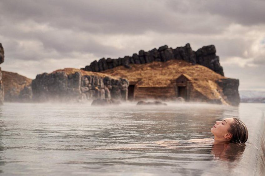 A person in a hot spring with a rocky landscape in the background. 3