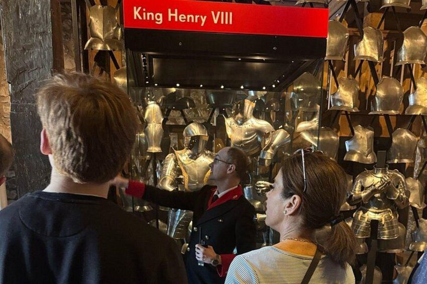 A museum exhibit with a red sign reading 'King Henry VIII' and numerous golden helmets on display. 2