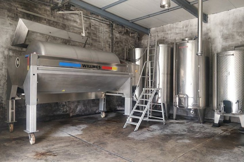 A stainless steel Willmes machine in a warehouse with metal tanks and a ladder. 2