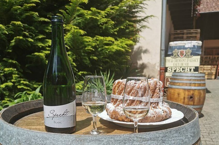 A bottle of Spacht white wine, a glass, and a plate of pastries on a stone table outdoors. 4