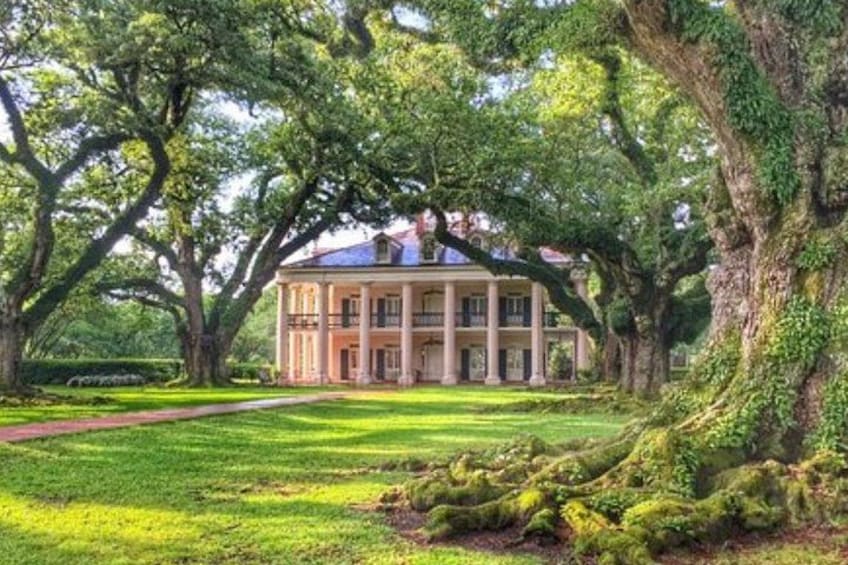 Una casa grande e histórica, con fachada simétrica, rodeada de abundante vegetación y árboles altos. 3