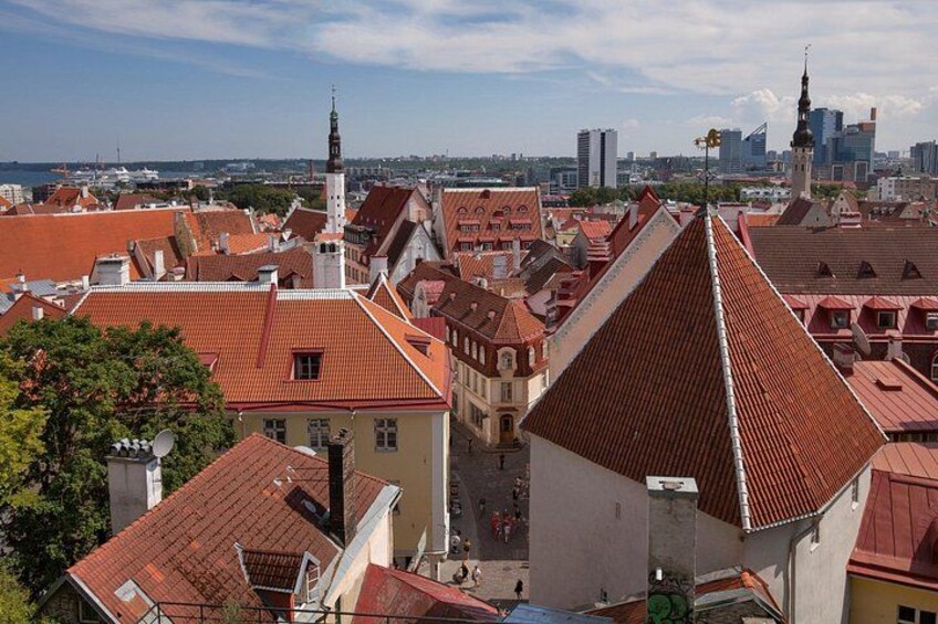 Eine Stadtansicht mit roten Dächern, einem markanten Kirchturm und einer modernen Skyline im Hintergrund. 3
