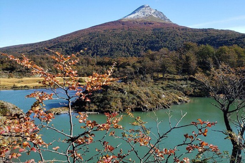 Un lago, árboles con hojas otoñales y una montaña al fondo. 2