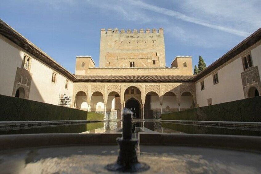 A courtyard with a fountain, arches, and a large tower. 3