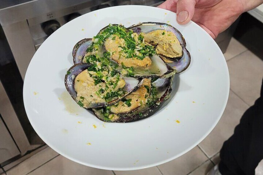 A plate of mussels garnished with herbs and lemon. 3
