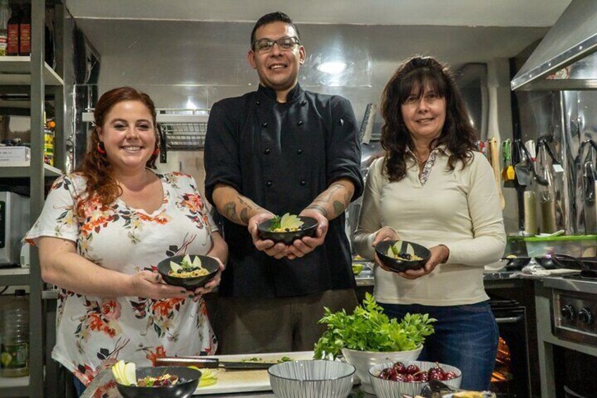 Three people in a kitchen holding bowls of food. 2