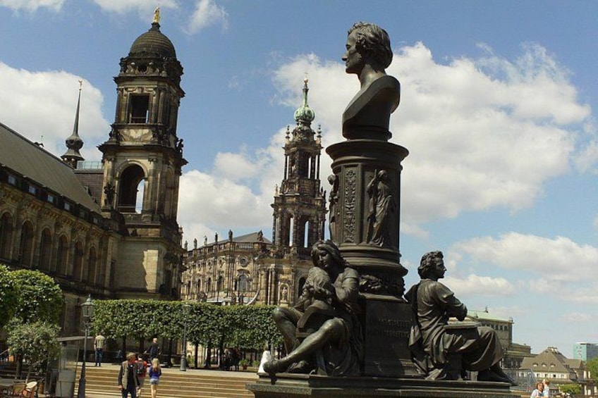 A statue of a seated figure, a large building with a dome, and a smaller tower. 5