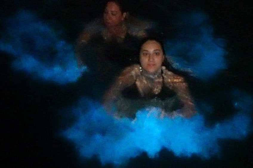 Two people in a body of water with blue lighting effects. 3