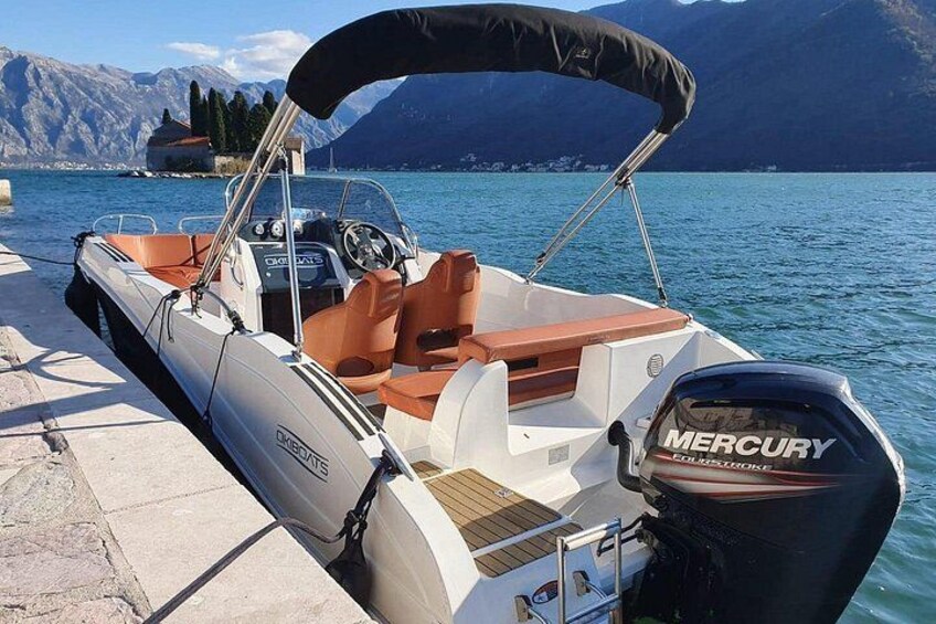 A motorboat docked at a pier with a mountainous backdrop. 3