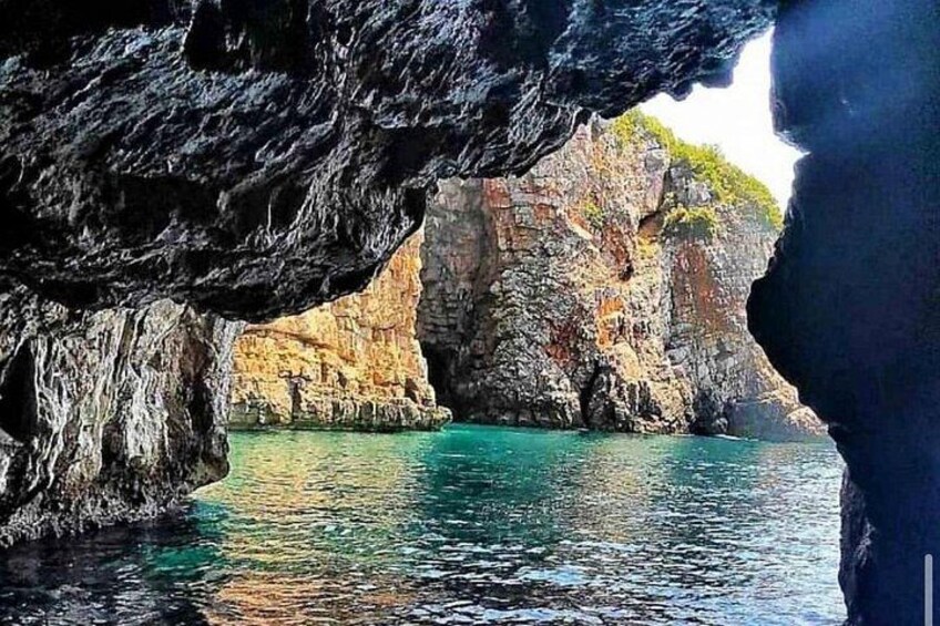 A coastal cave entrance with clear turquoise water and rocky cliffs. 1