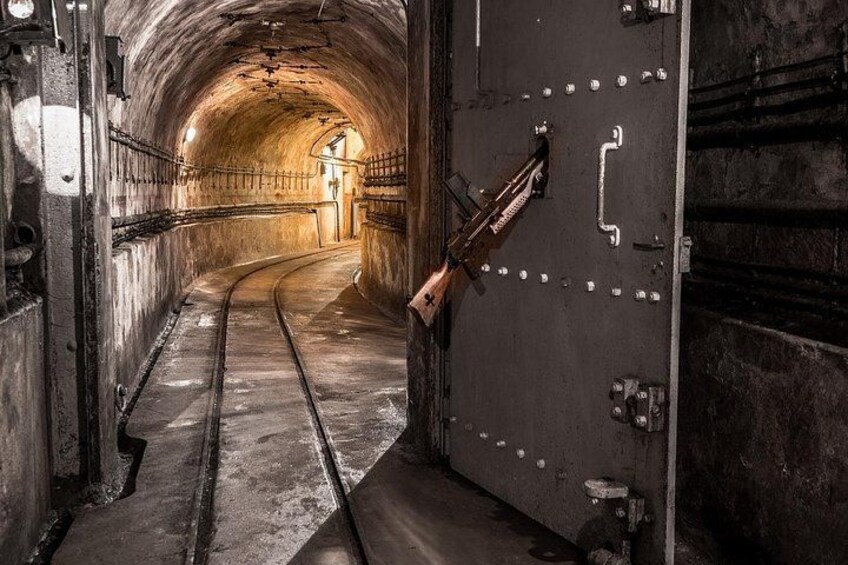 En tunnel med en buet bane, metalgelændere og en stor ståldør. 2