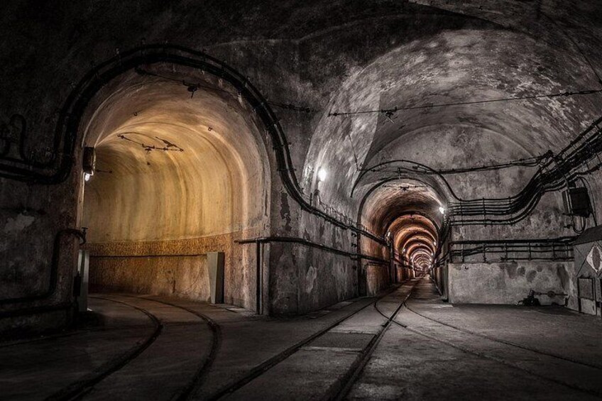Un tunnel aux plafonds en arc de cercle, aux murs en béton et doté d’un éclairage suspendu. 3