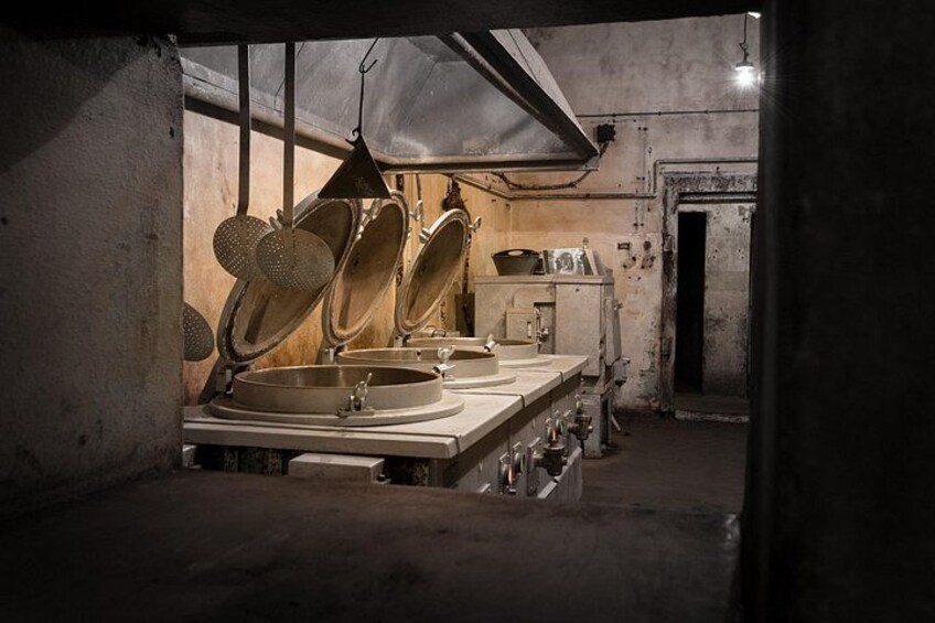 Een keuken in gedempt licht, met grote pannen, een spoelbak en een fornuis. 3