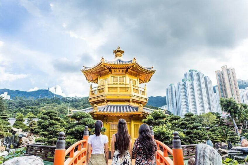 A traditional golden pagoda with a bridge in the foreground and modern buildings in the background. 1