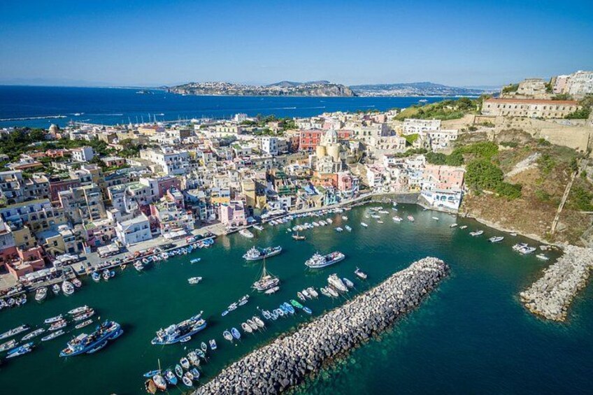 A coastal town with colorful buildings, a harbor filled with boats, and a rocky breakwater. 2