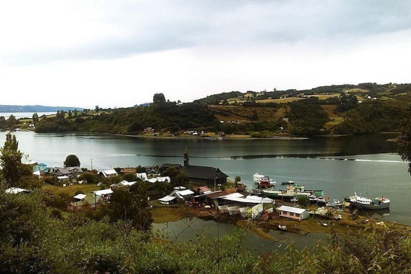 Un village au bord d’un lac, avec des bateaux, des maisons et un paysage vallonné. 3