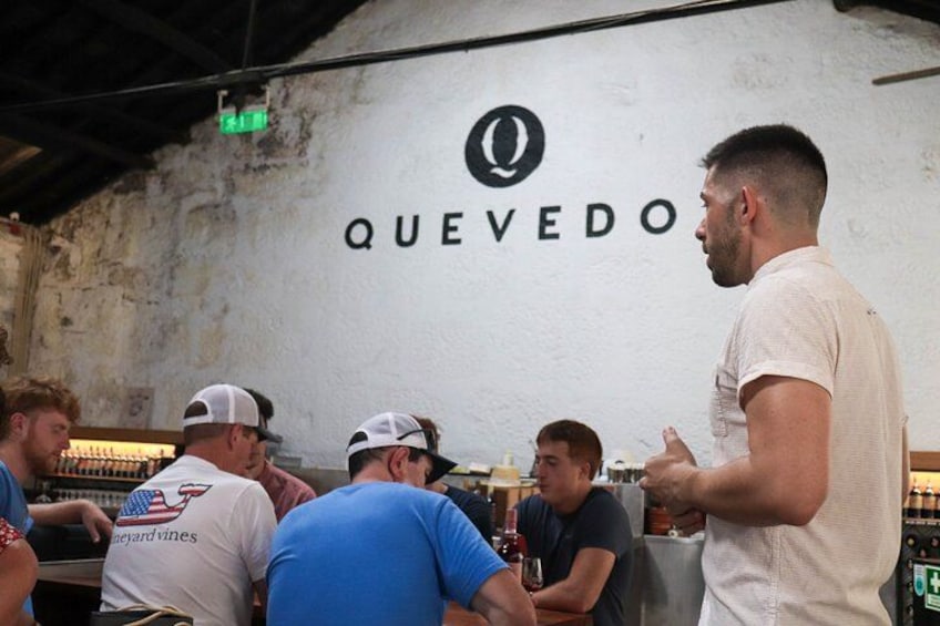 A group of people at a bar with a sign that reads 'QUEVEDO' on the wall. 2