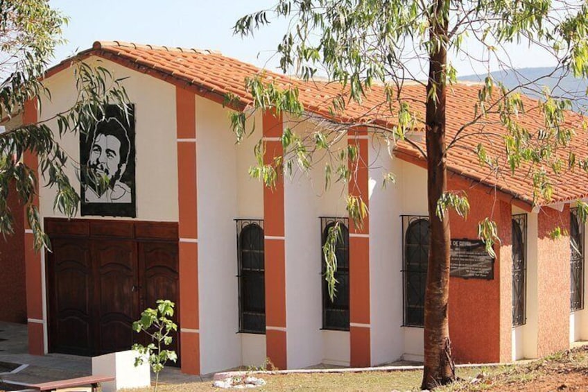 Un bâtiment avec un toit en tuiles, une fresque murale et un arbre devant. 1