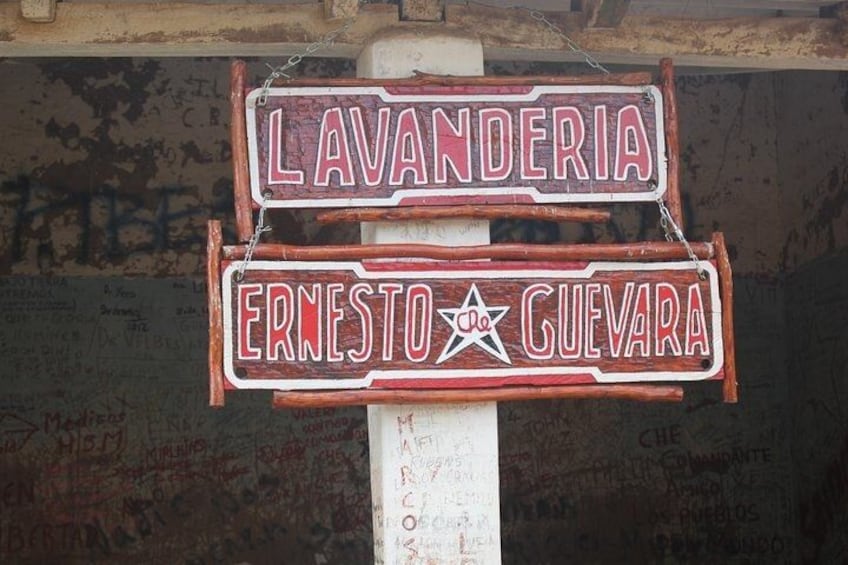Un letrero con las palabras 'LAVANDERIA' y 'ERNESTO GUEVARA' y un símbolo de estrella. 2