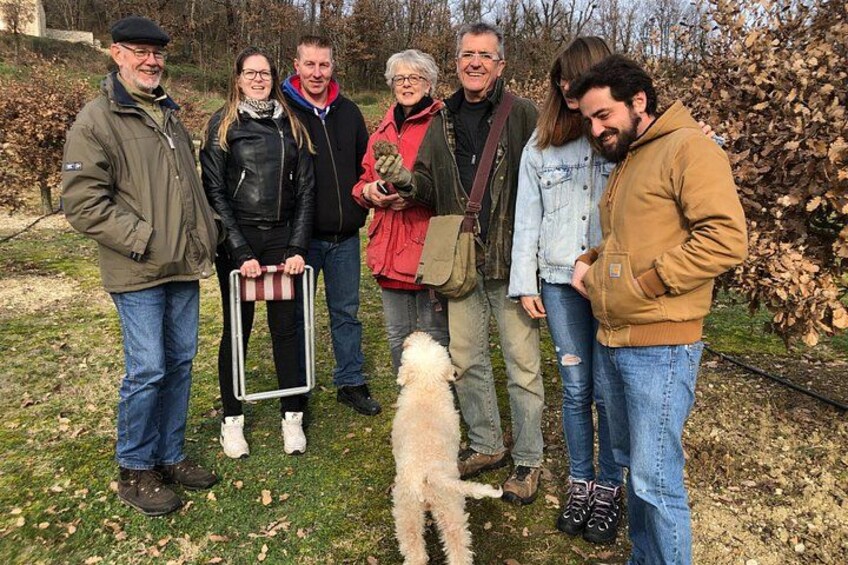 A group of people standing outdoors with a dog in a grassy area. 1