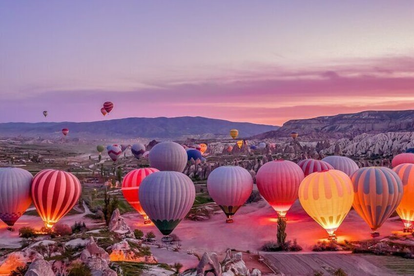 Un paisaje con numerosas globos aerostáticos de diversos colores, con montañas y un cielo al atardecer. 4