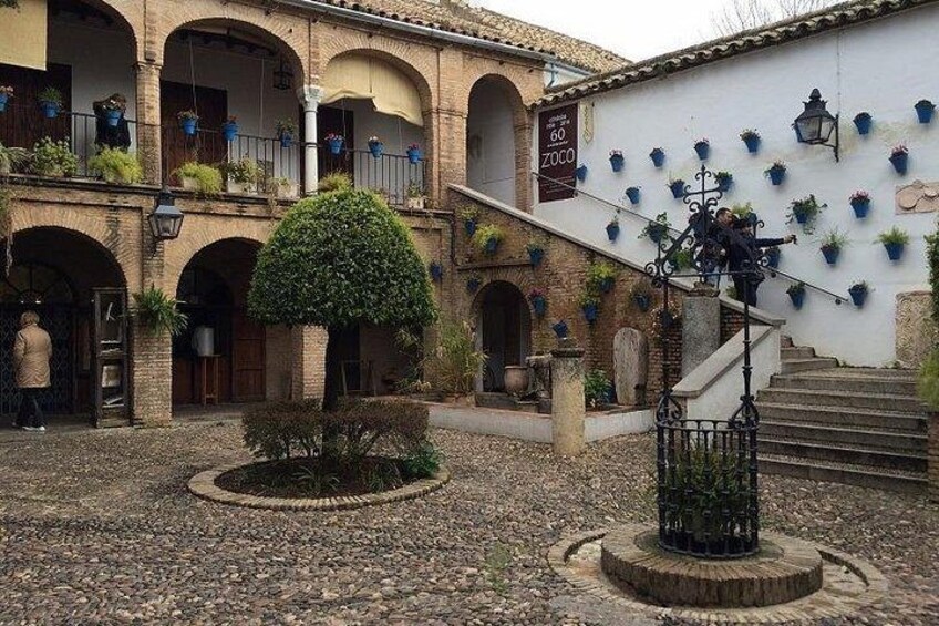 A courtyard with a central tree, a staircase, and a building with a sign. 2