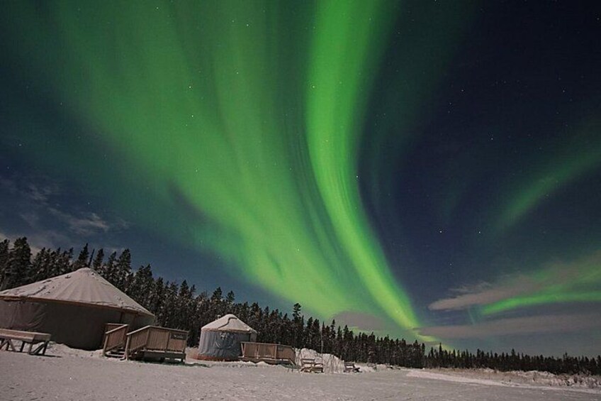 Un paysage enneigé avec une yourte et une tente, et des aurores boréales dans le ciel. 1