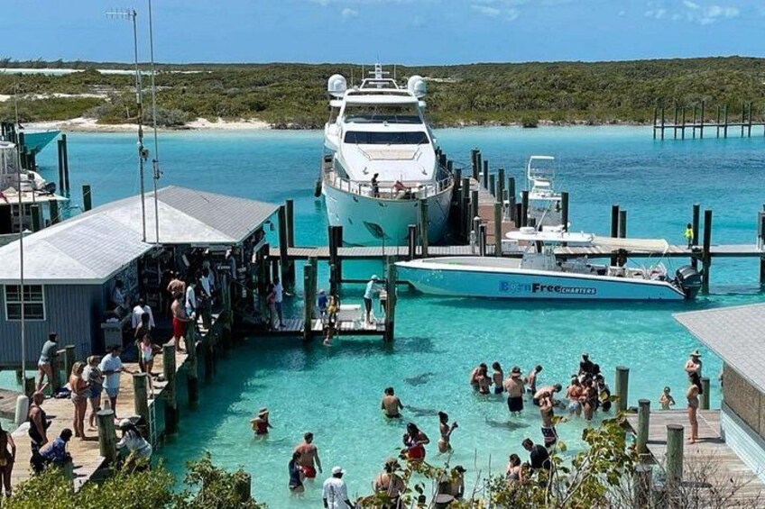 A marina with boats docked, people swimming, and a pier with a building. 2
