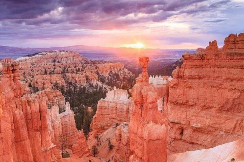 Un canyon aux formations rocheuses rouges, avec un coucher de soleil en arrière-plan. 2