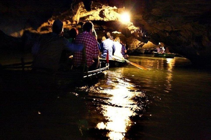 Persone su una barca in un fiume di notte, con una grotta sullo sfondo. 4