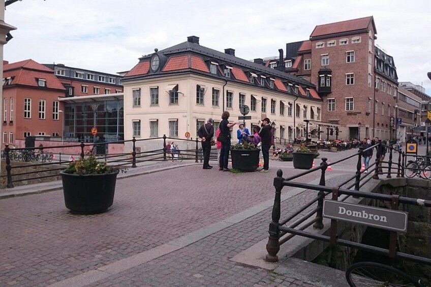 A cobblestone street with buildings, a sign reading 'Dombron,' and people walking. 3