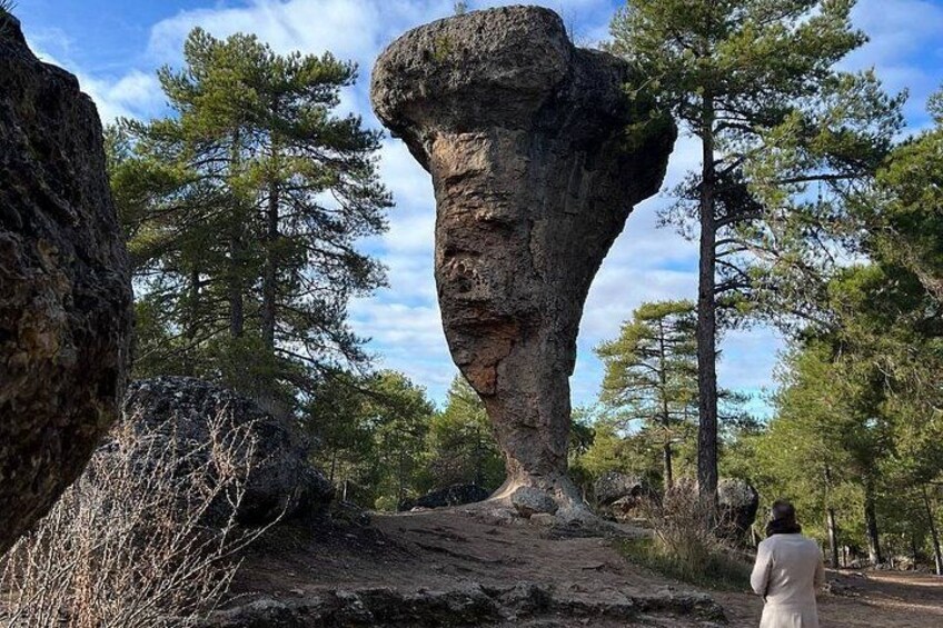 A large rock formation with a person standing in the foreground. 1