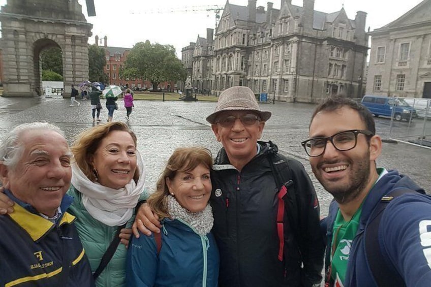 A group of people taking a selfie in a historic square with buildings and an archway in the background. 5