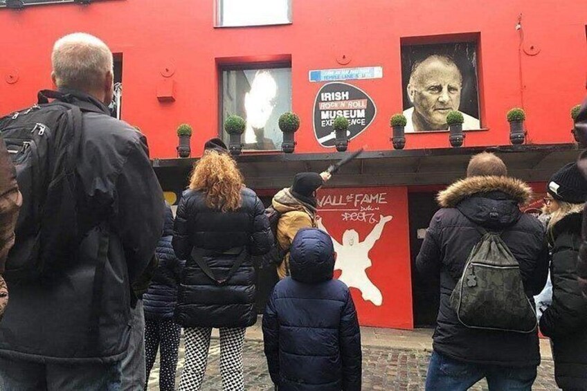 A red building with a mural and a sign that reads 'Irish Rock 'n' Roll Museum Experience.' 4