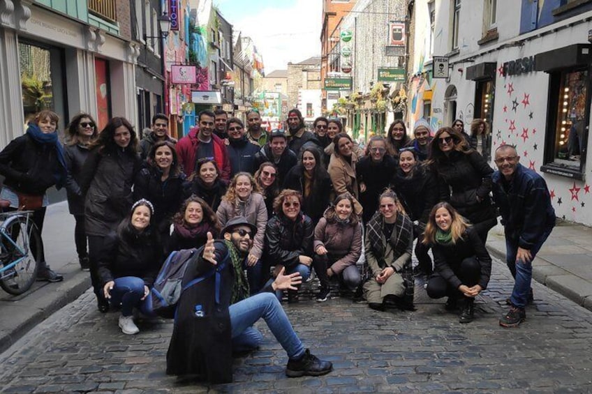A group of people posing on a cobblestone street with shops and signs in the background. 3
