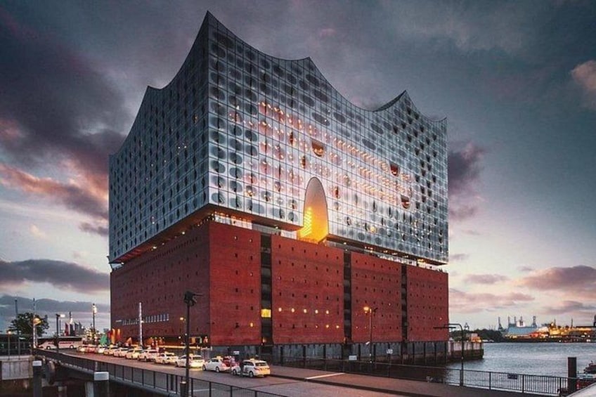 Un edificio moderno con un tetto curvo distintivo e un ampio ingresso centrale. 1