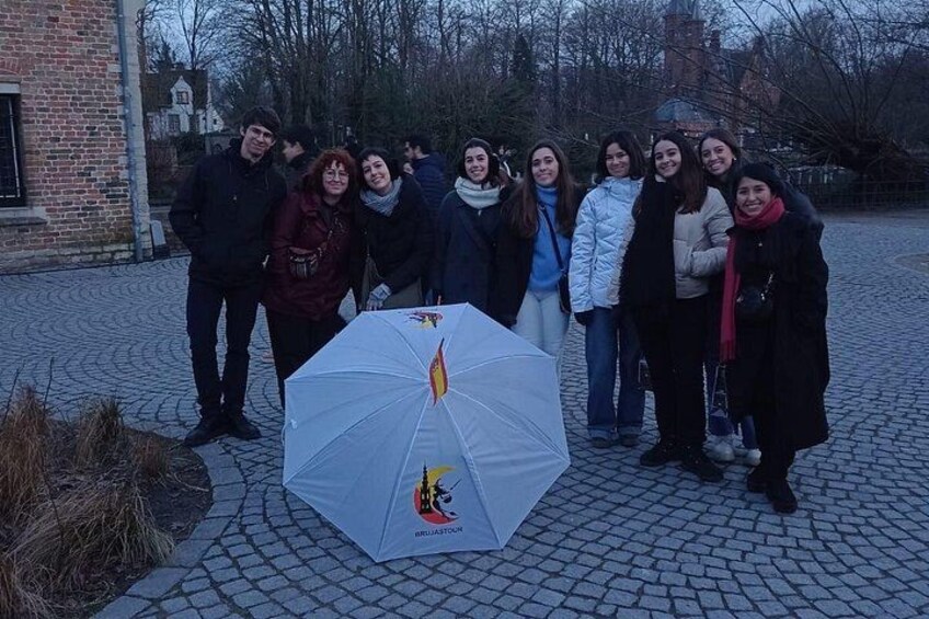 A group of people standing in a cobblestone area with a white umbrella featuring a cartoon character. 2
