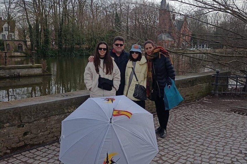 Un groupe de personnes se tient au bord d’une rivière, avec un pont en arrière-plan. 3