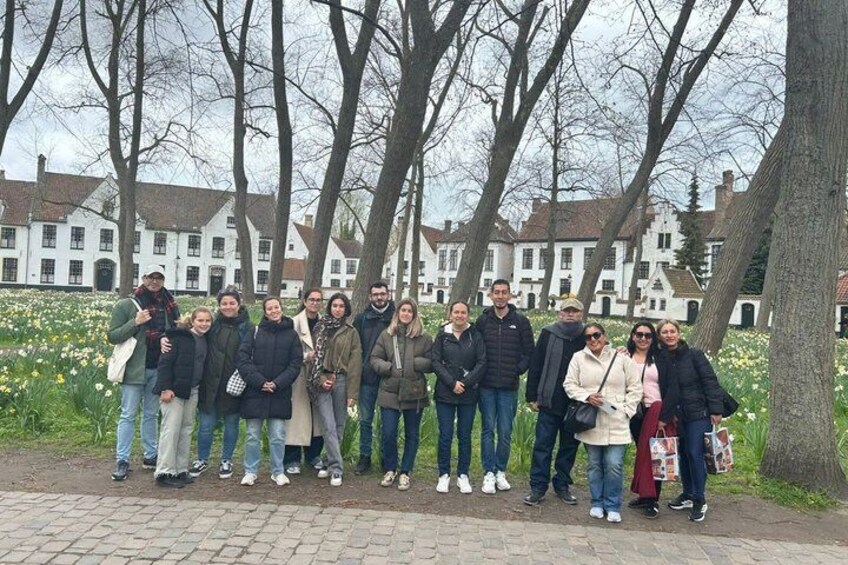 Un groupe de personnes se tient sur un chemin pavé, avec des arbres et des bâtiments en arrière-plan. 2