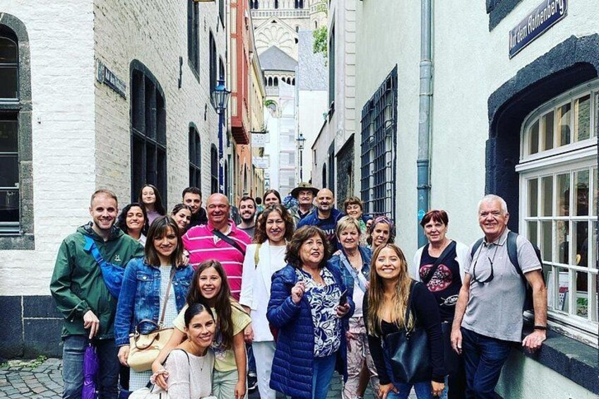 Een groep mensen staat op een kinderkopjesstraat in een historische plaats. 2