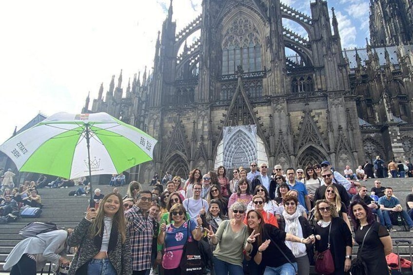 En gruppe mennesker poserer foran en gotisk katedral med detaljeret arkitektur. 1