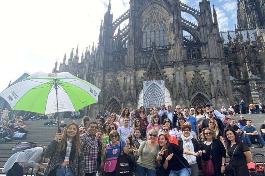 Un grupo de personas posando frente a una catedral grande y ornamentada con detallada arquitectura gótica. 1