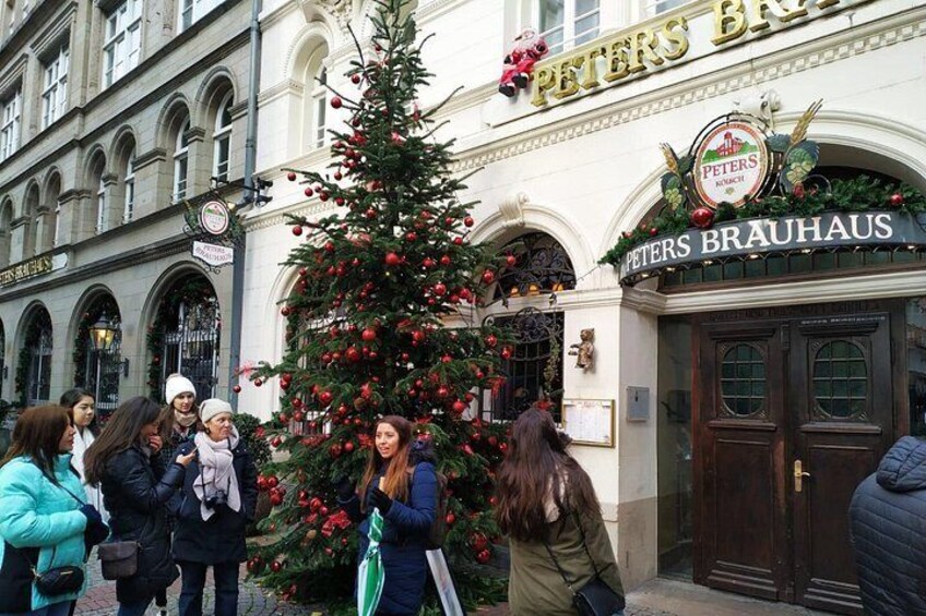 Un sapin de Noël devant le Peters Brauhaus, un bâtiment doté de fenêtres en arc de cercle et d’une enseigne. 2