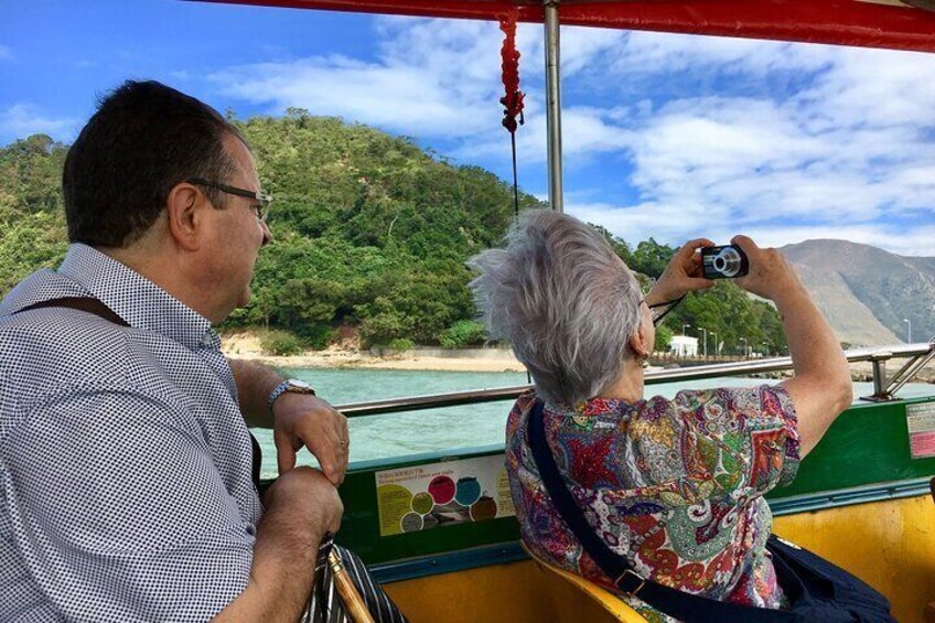 A person taking a photo of a coastal landscape with mountains in the background. 5